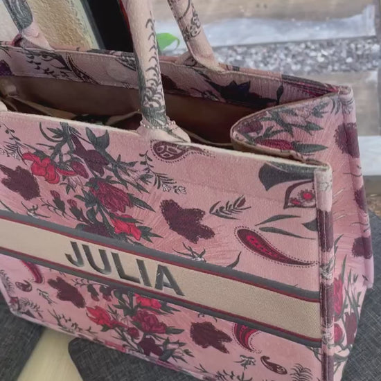 Structured personalized canvas book tote with embroidered name and elegant floral paisley design in blush pink and burgundy tones.