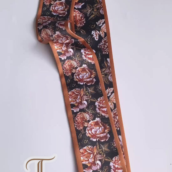 Video showcasing a vintage rose floral twilly scarf with rust, terracotta and cream flowers on a deep black background.