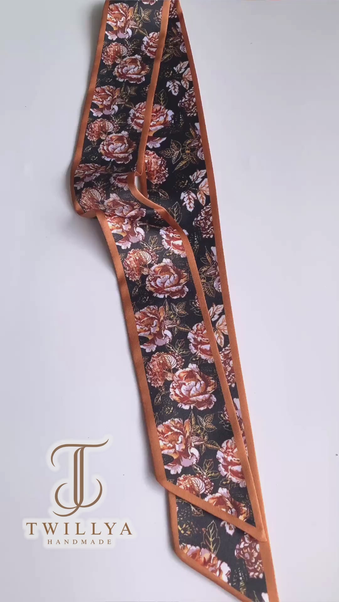 Video showcasing a vintage rose floral twilly scarf with rust, terracotta and cream flowers on a deep black background.