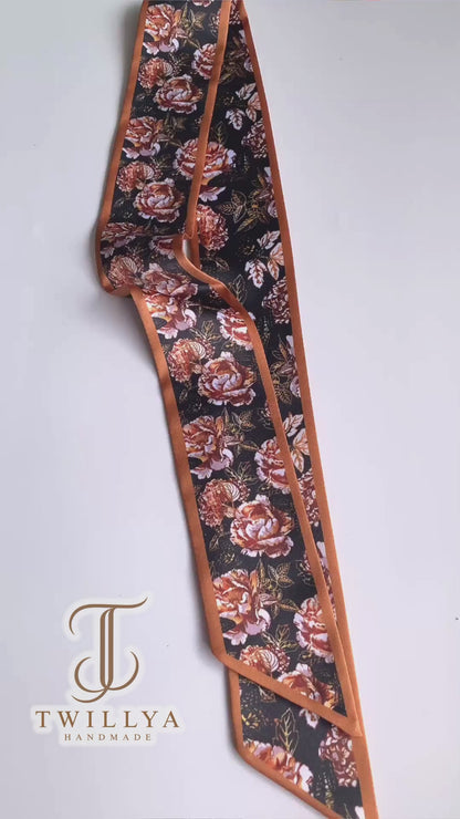 Video showcasing a vintage rose floral twilly scarf with rust, terracotta and cream flowers on a deep black background.