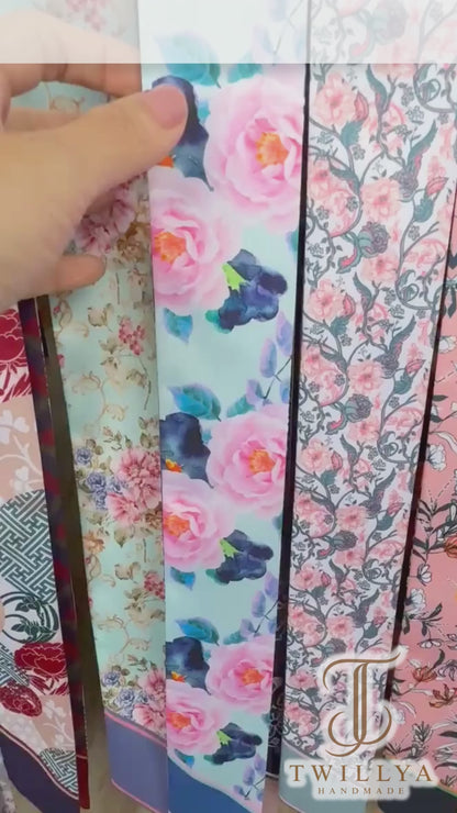 Video showing a watercolour floral twilly scarf with aqua, pink and contrasting navy ornamental patterns