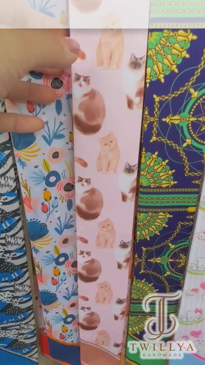 Video showing a pastel cat lovers twilly scarf with playful illustrated cats in pink, cream and orange colourways.