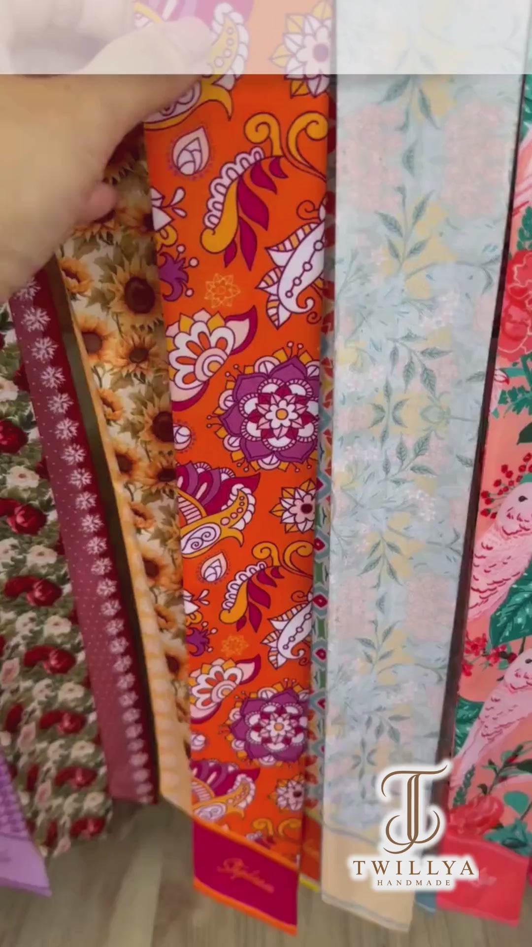 Colorful bohemian twilly scarf showcasing intricate mandala-inspired flowers, orange paisley patterns, and vibrant turquoise geometric details. Finished with personalized name printing on contrasting pink and coral pointed ends, this versatile skinny scarf adds a playful retro touch to handbags, hairstyles, and everyday outfits.