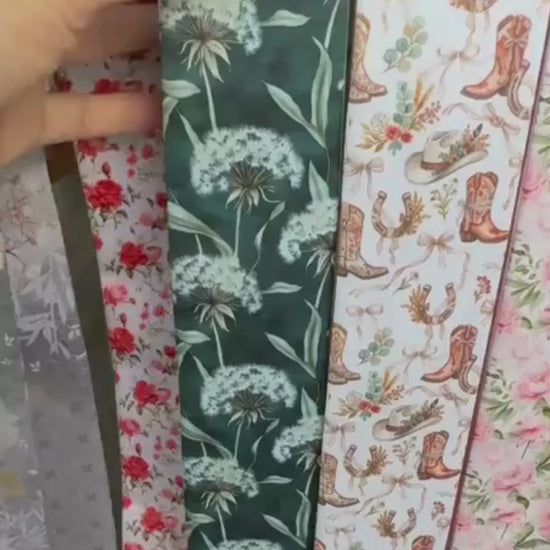 Close-up video of sage green botanical skinny scarf featuring delicate white dandelion illustrations and elegant soft green detailing 