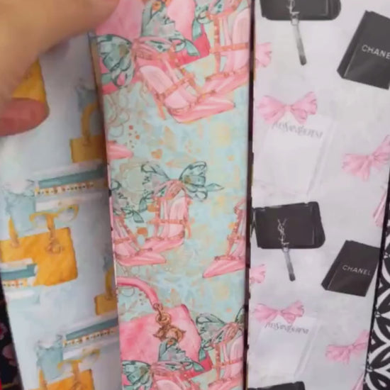Personalized satin twilly scarves featuring pastel pink and turquoise designs with beauty-inspired motifs, including lipstick, makeup brushes, perfume bottles, and handbags. Each scarf is finished with the custom name "Tracey" on its pointed end and styled elegantly on a soft cream background.