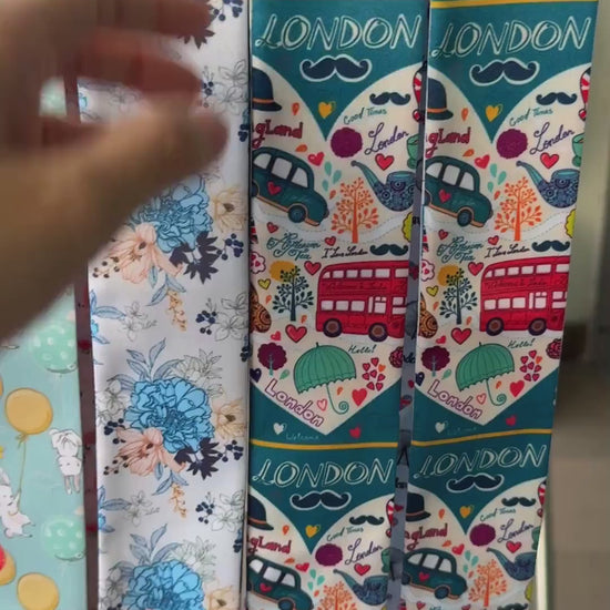 London-themed twilly scarf showcasing iconic red double-decker buses, Big Ben, the London Eye, telephone booths, black taxis, and colorful travel illustrations. A versatile skinny scarf for handbags, hair styling, and gifts for London lovers.