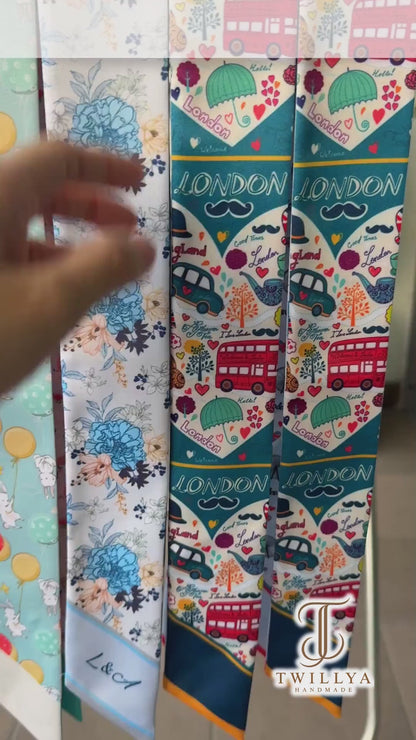London-themed twilly scarf showcasing iconic red double-decker buses, Big Ben, the London Eye, telephone booths, black taxis, and colorful travel illustrations. A versatile skinny scarf for handbags, hair styling, and gifts for London lovers.